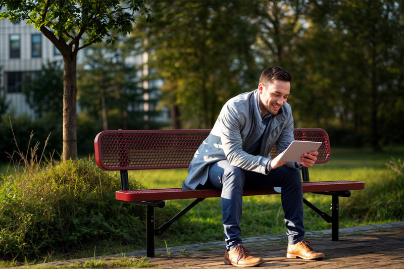 Man sitting on a bench in a park using a tablet