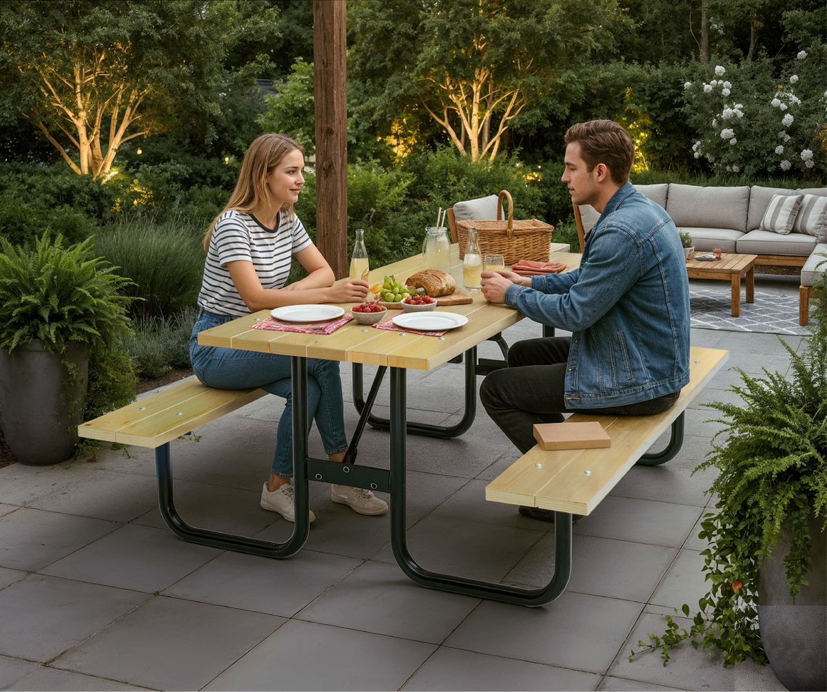 Two people sitting at a wooden picnic table in a garden setting.