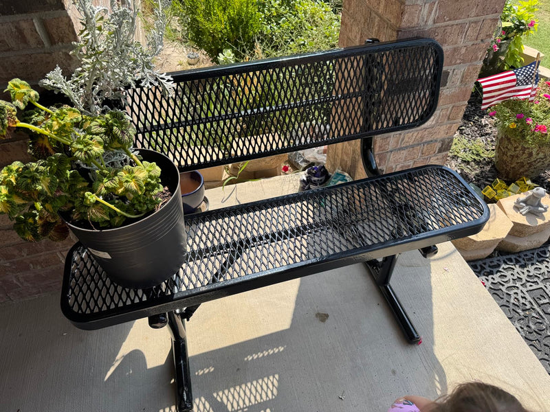 Black metal bench with a potted plant on a patio